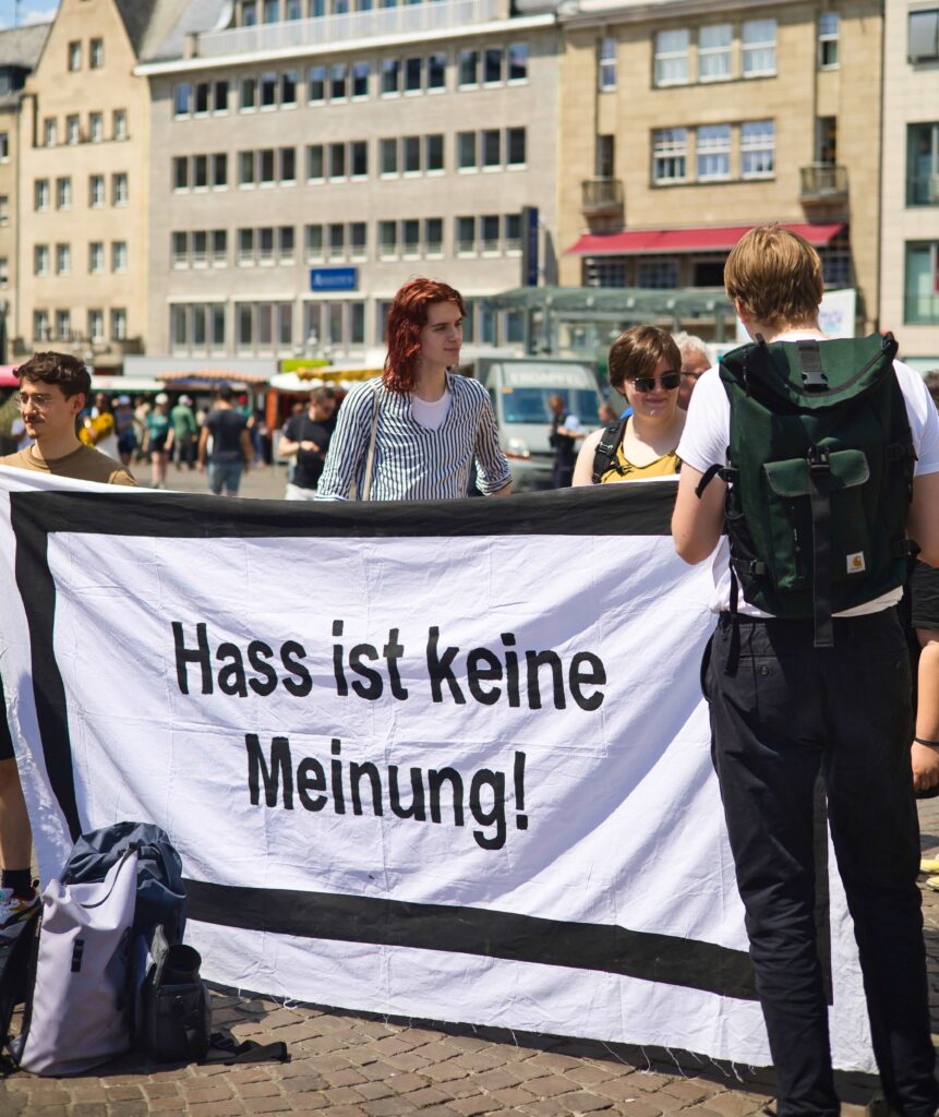 Zwei Menschen halten ein Banner mit der Aufschrift "Hass ist keine Meinung!"